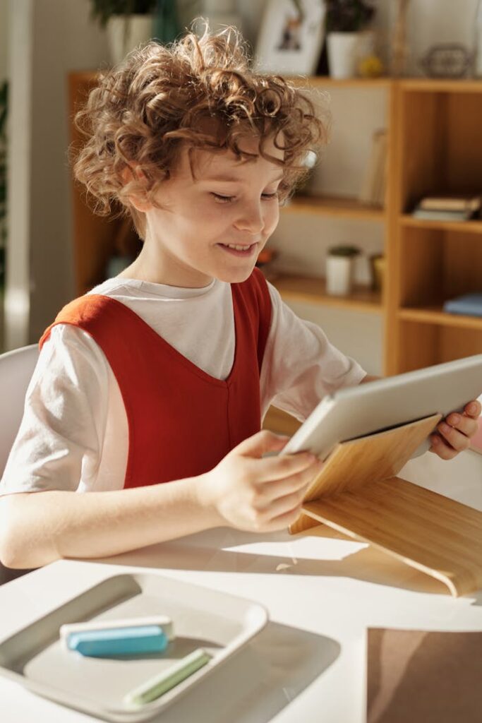 A happy child using a tablet for online education at home during the day.